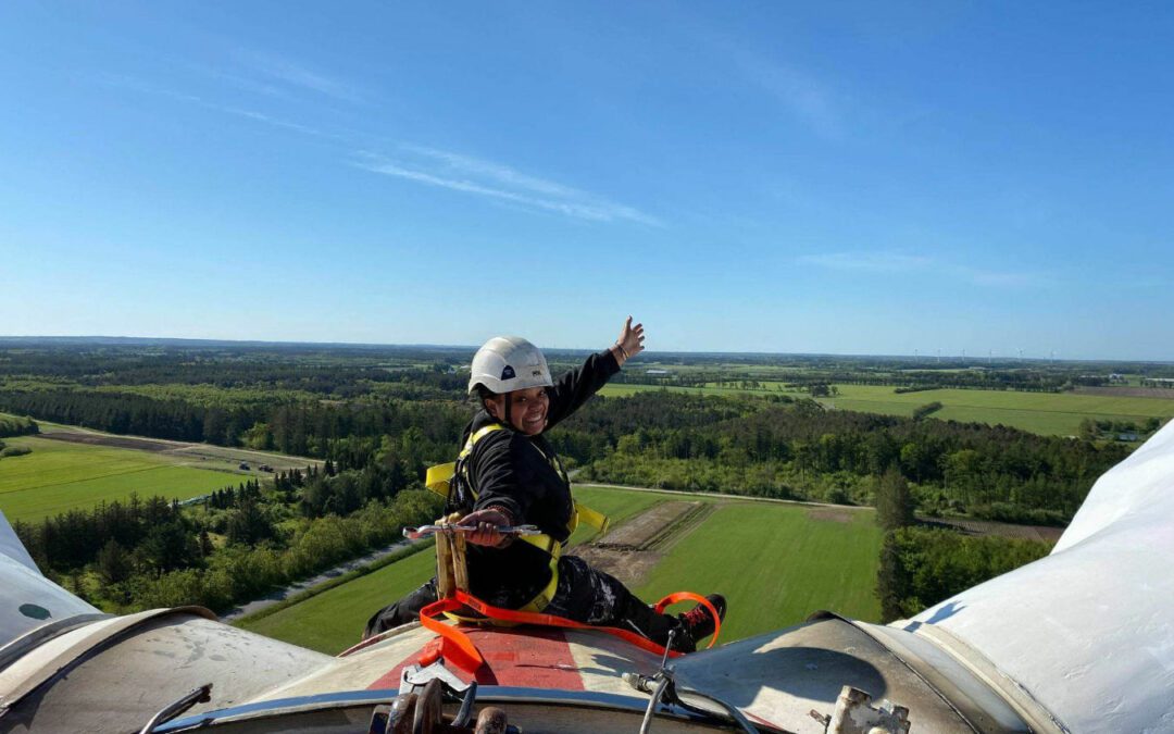 One person in hardhat and wearing a security harness on the top of the nacelle of Tvindkraft wind mill