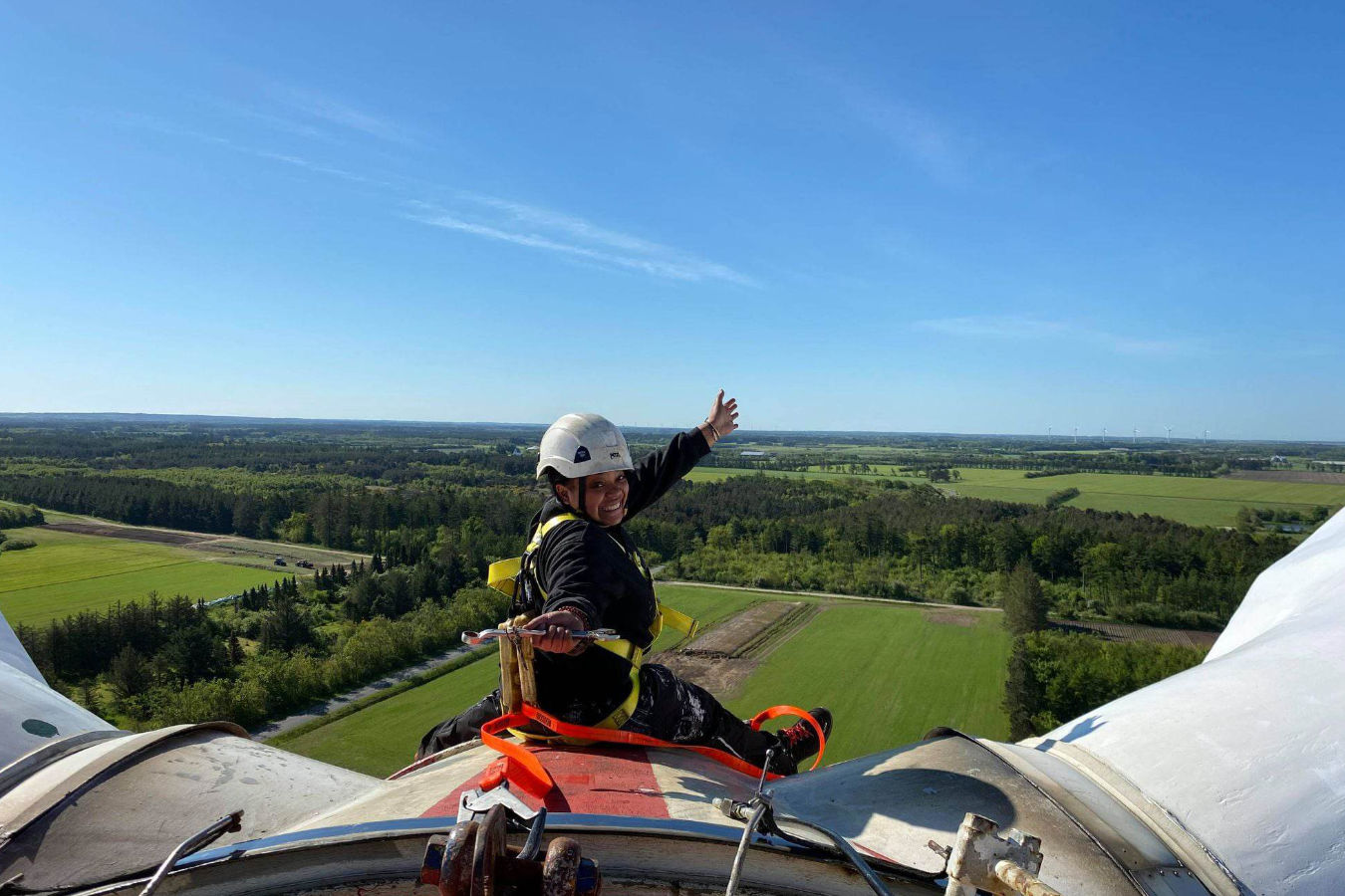 One person in hardhat and wearing a security harness on the top of the nacelle of Tvindkraft wind mill