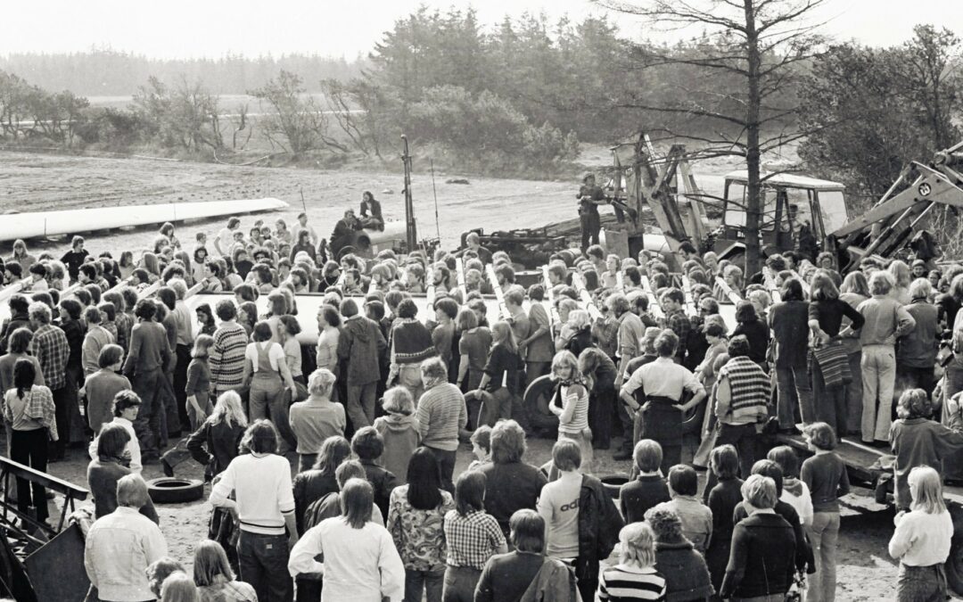 A black and white photo from the 1970s of large group of windmill builders carrying a 27m blade