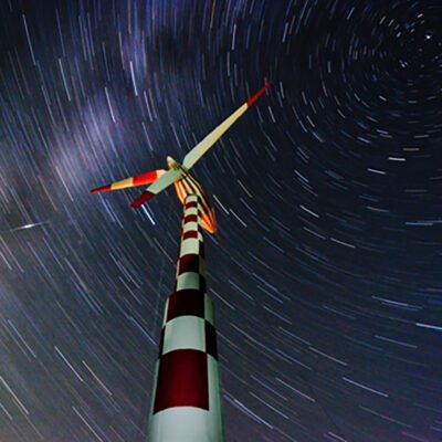 Tvindmill and starry sky photographed using time lapse so the stars look like lines